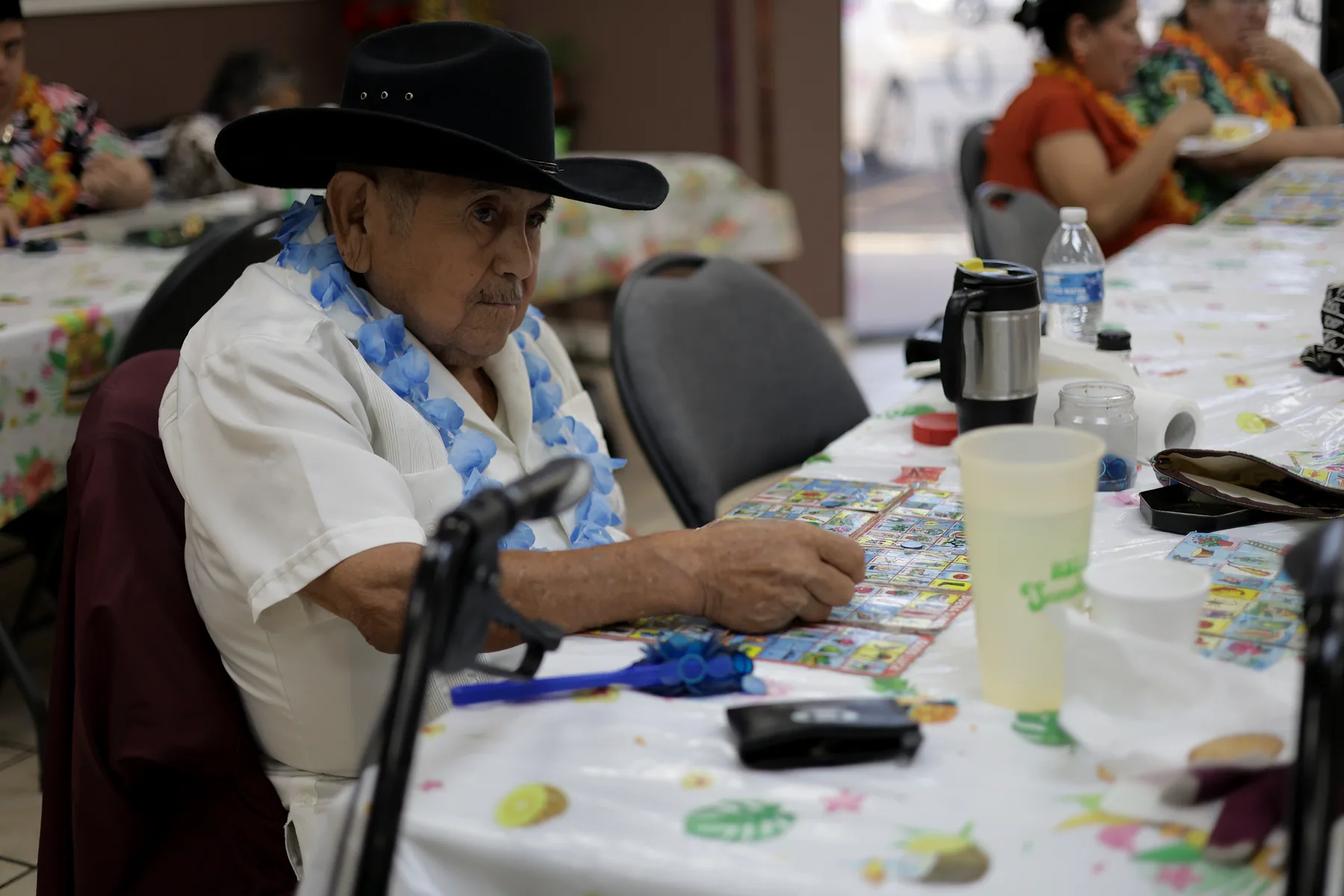 A participant in a black hat concentrating on his lotería board